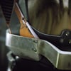 Armure métallique détaillée avec des marques d'usure, insérée dans un environnement flou et sombre.